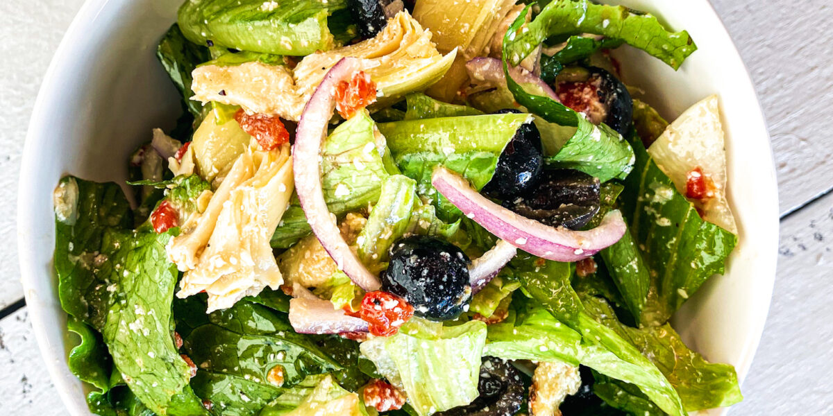 Pasta House Italian Salad with black olives, red onions and artichokes in a bowl