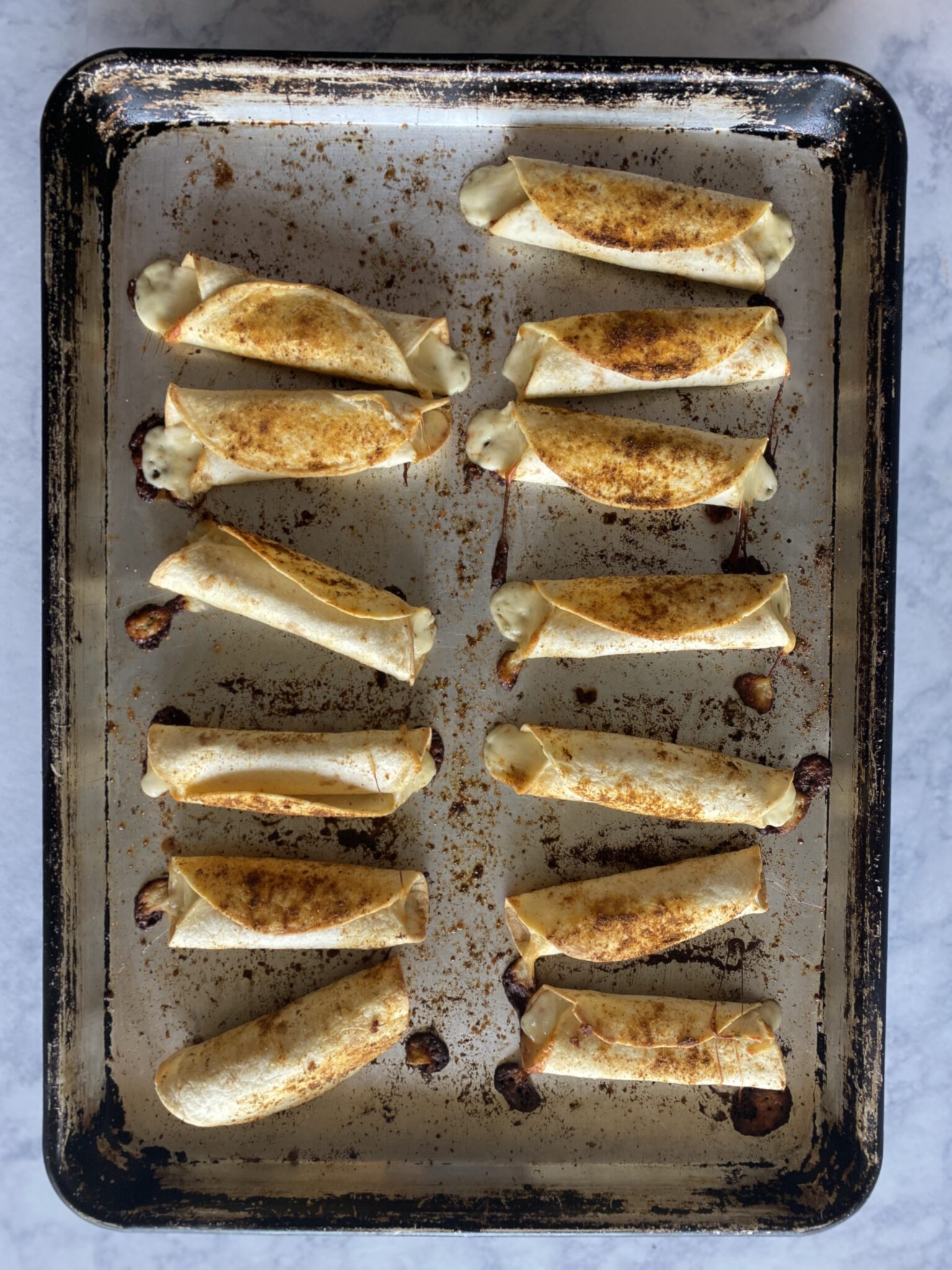 fish taquitos folled up and seasoned on a sheet pan-and baked