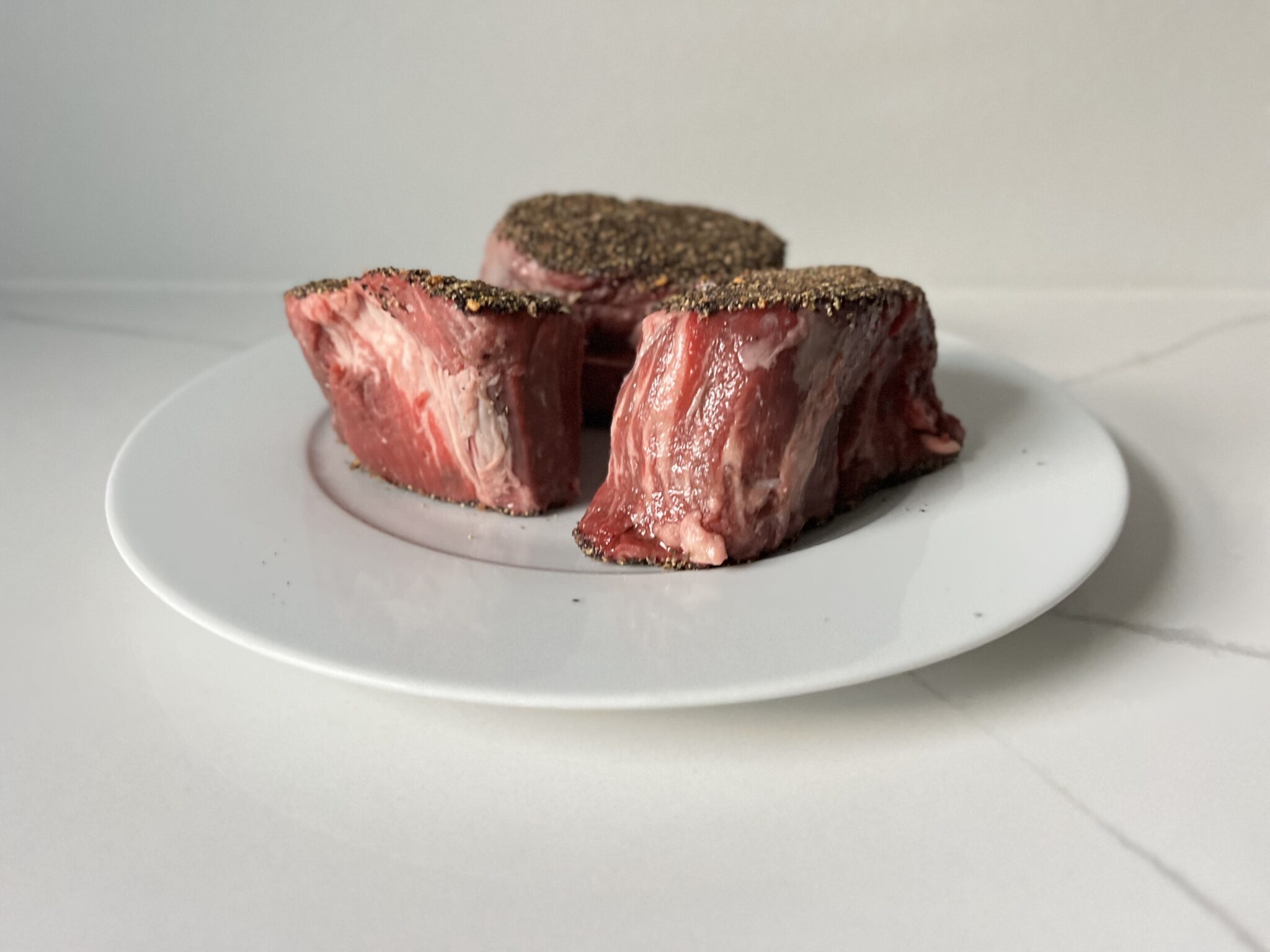 3 raw filet mignon steaks seasoned with salt and pepper
