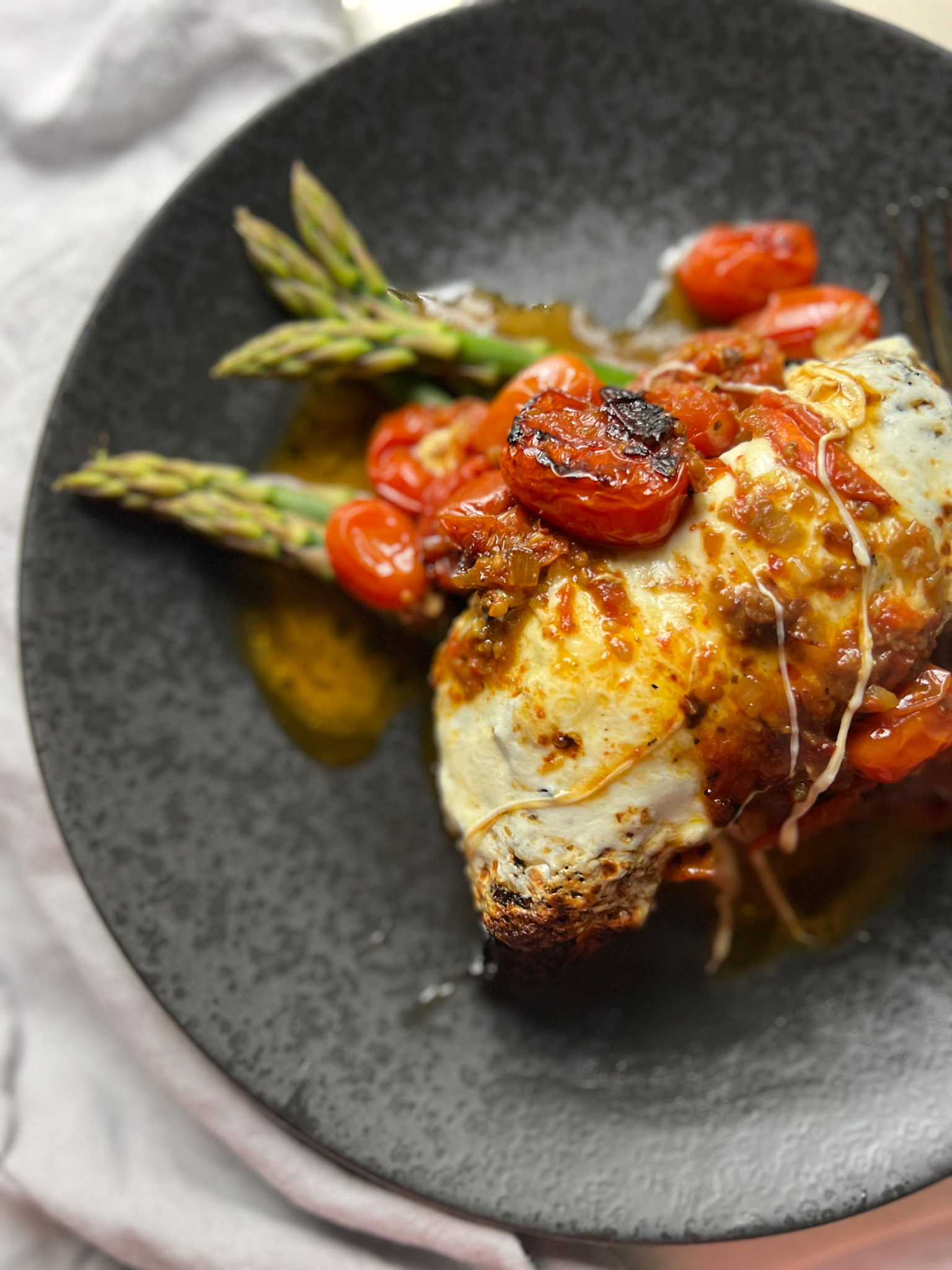 caprese grilled chicken on a plate over asparagus