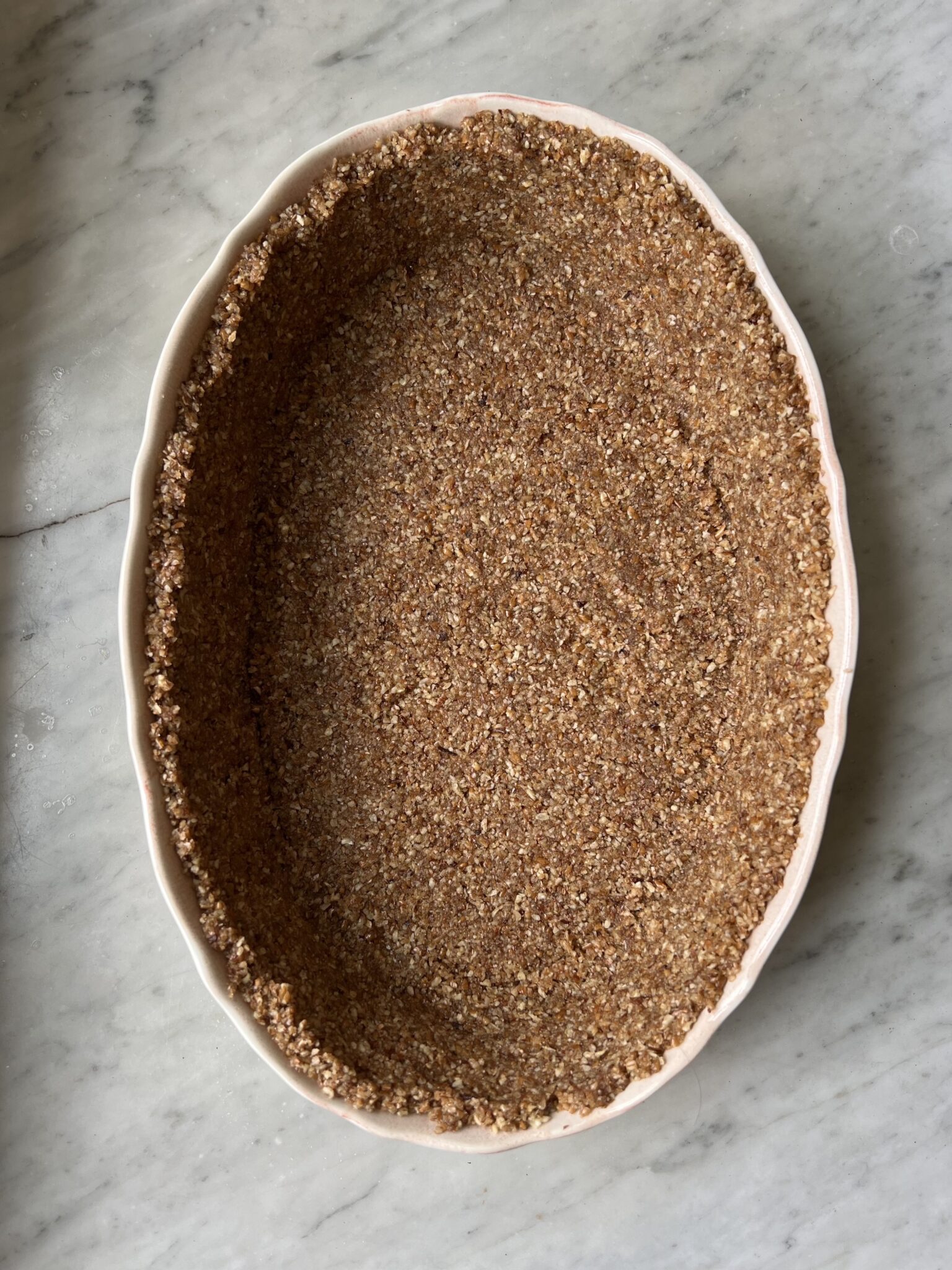 gluten-free pecan crust in an oval white pan baked