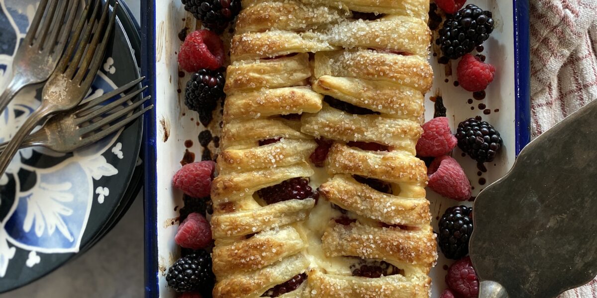 berry and cream cheese danish on a tray with berries and a blue plate