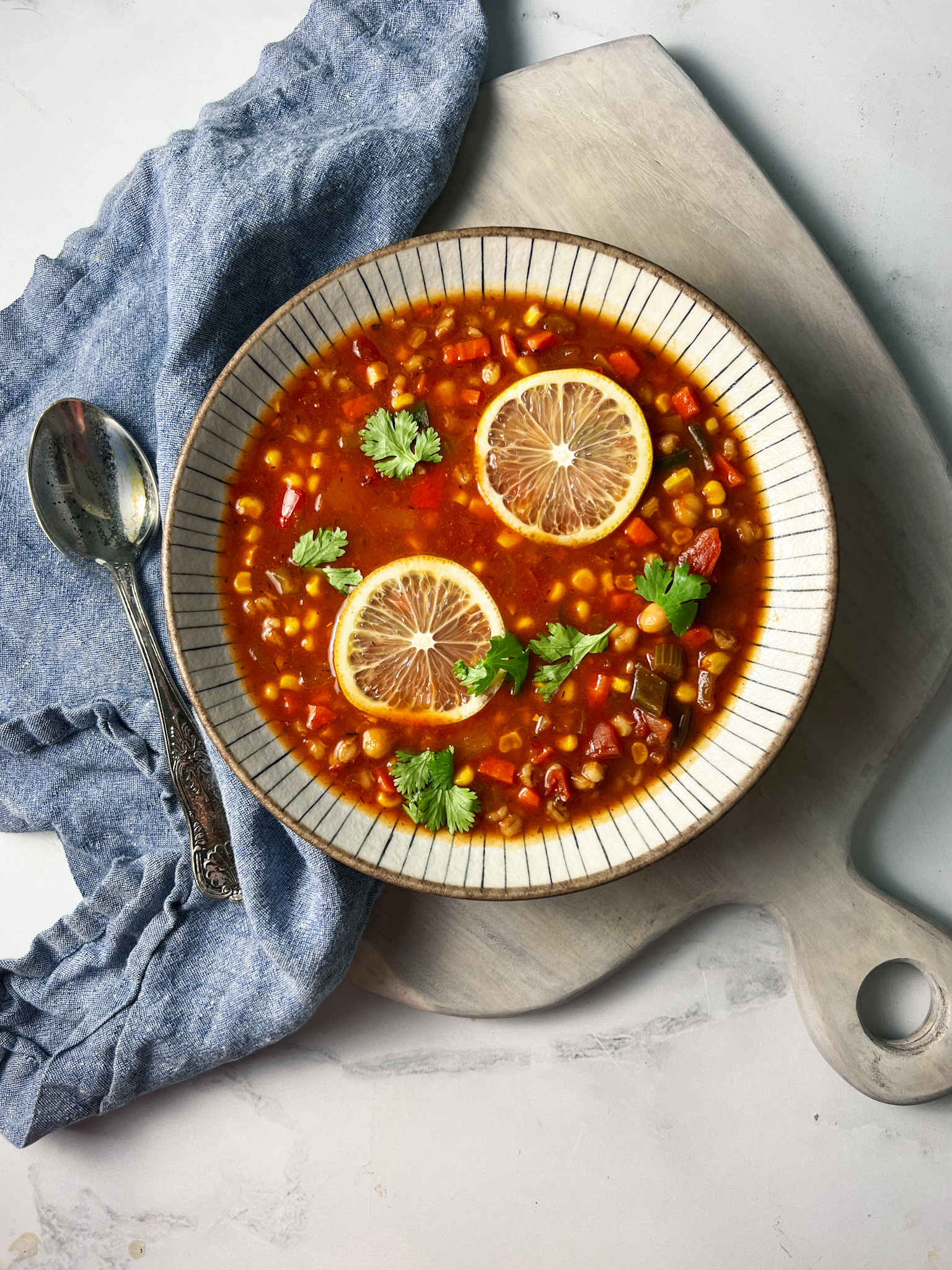 Bowl of Panera 10 vegetable soup with lemons in a bowl with a blue napkin.