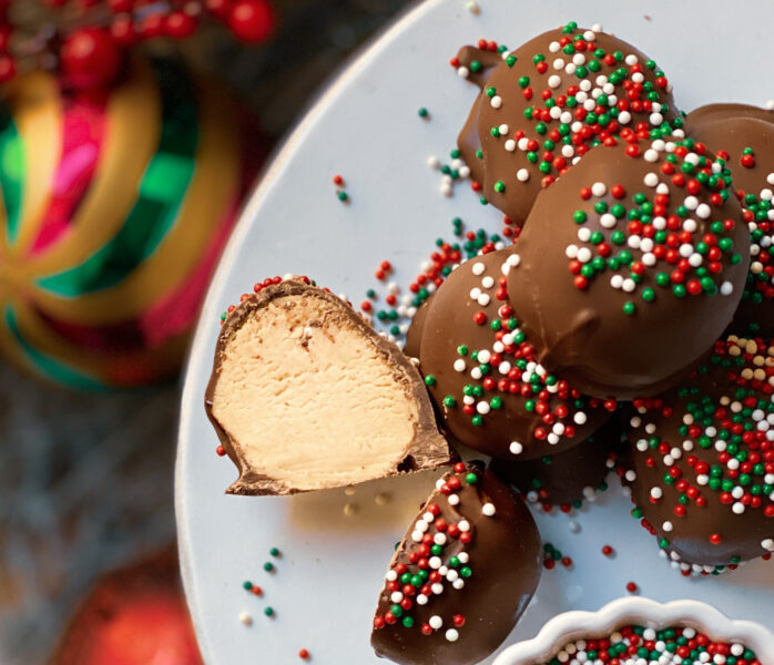 old-fashioned peanut butter balls dipped in chocolate with sprinkles and one cut open on a plate with sprinkles