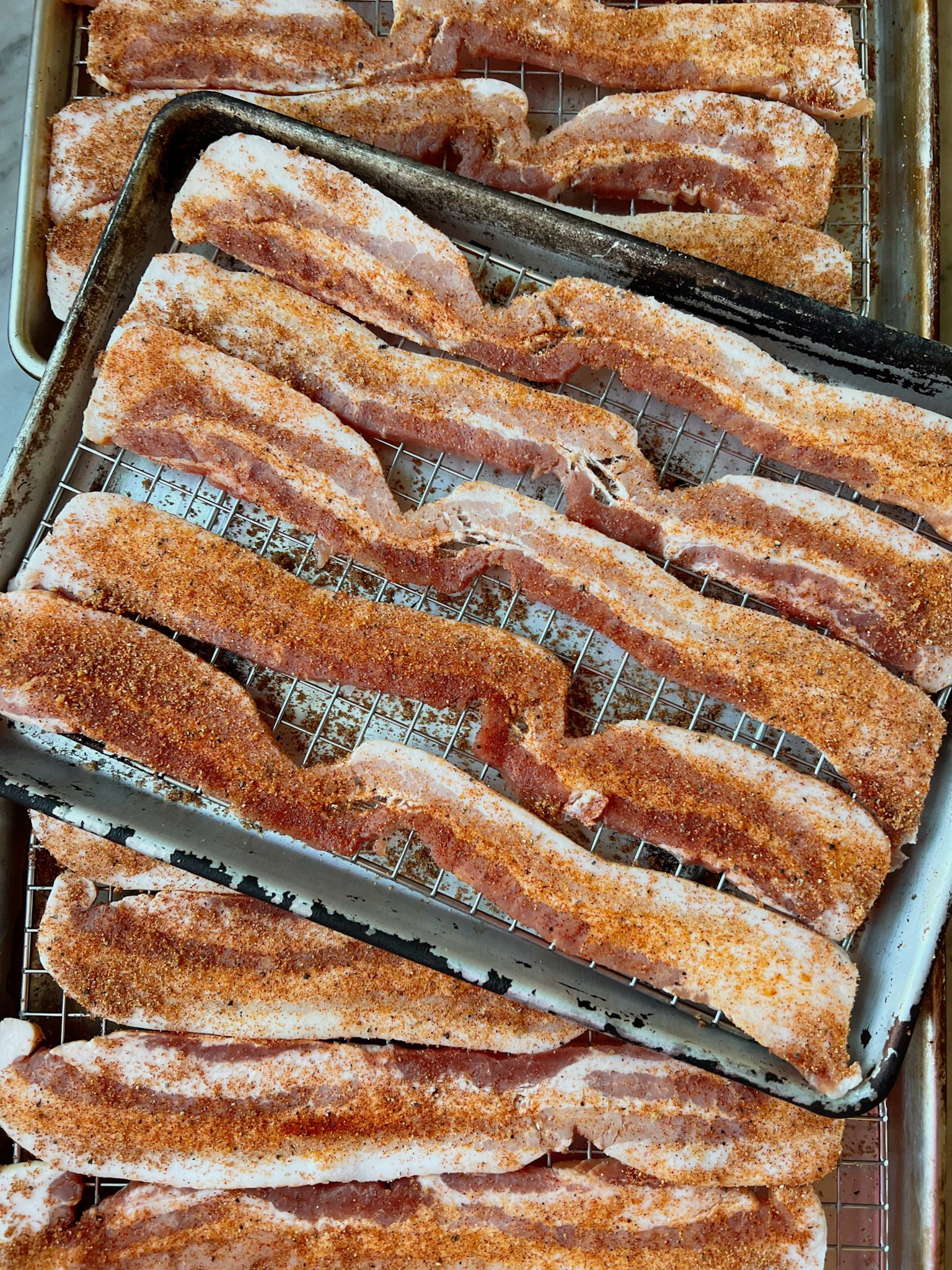 thick cut bacon in pans on smoking grates with seasoning