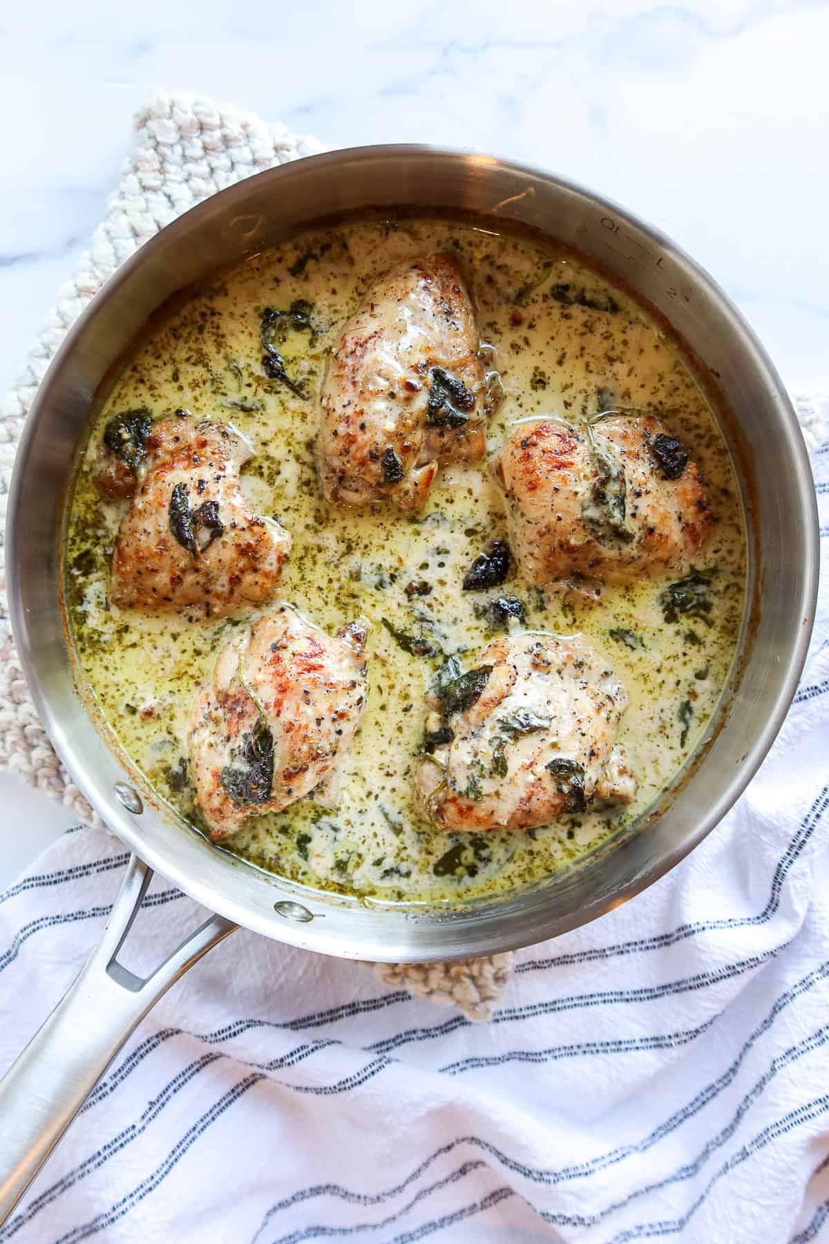 One skillet chicken thighs in a pan with creamy spinach sauce