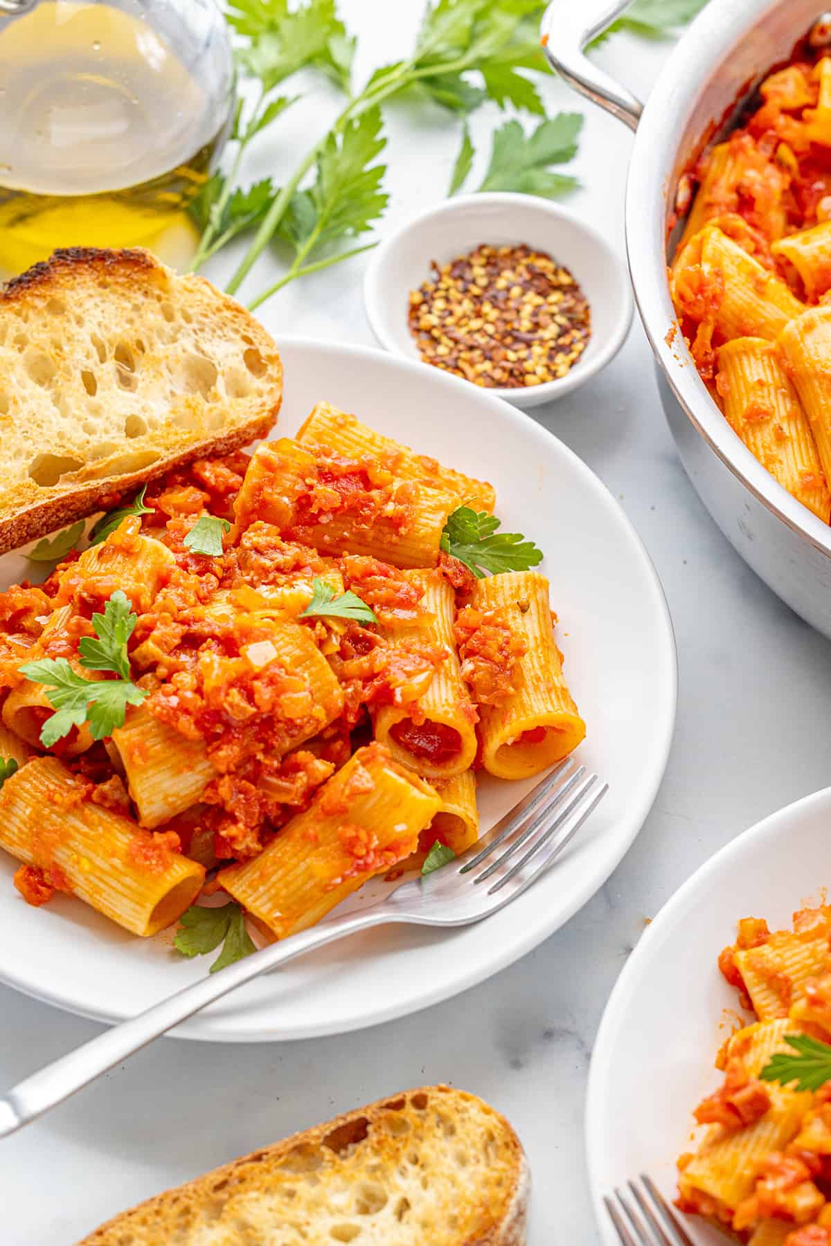 rigatoni all amatriciana on a plate with bread and spices
