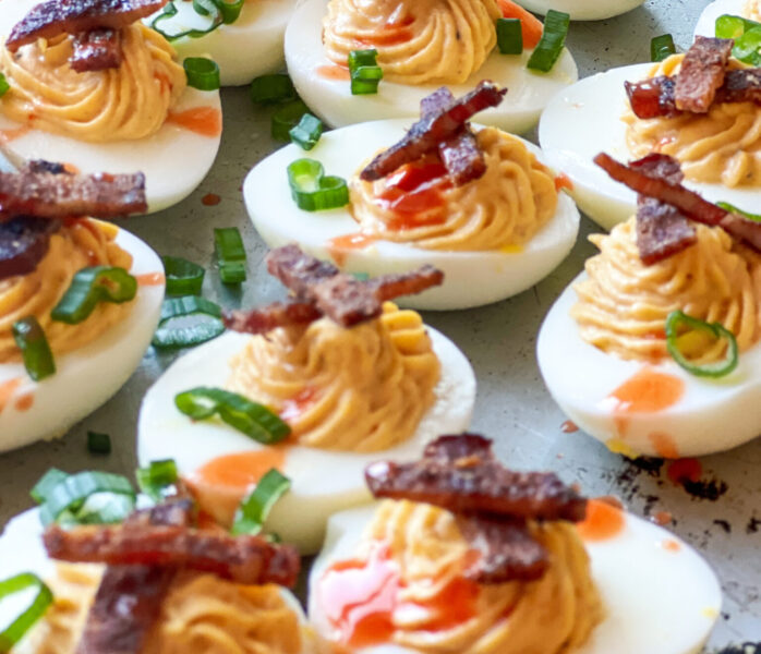 Smoked Deviled Eggs with Smoked Bacon Candy and Green onions and hot sauce