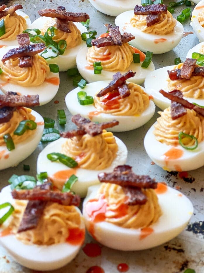 Smoked Deviled Eggs with Smoked Bacon Candy and Green onions and hot sauce