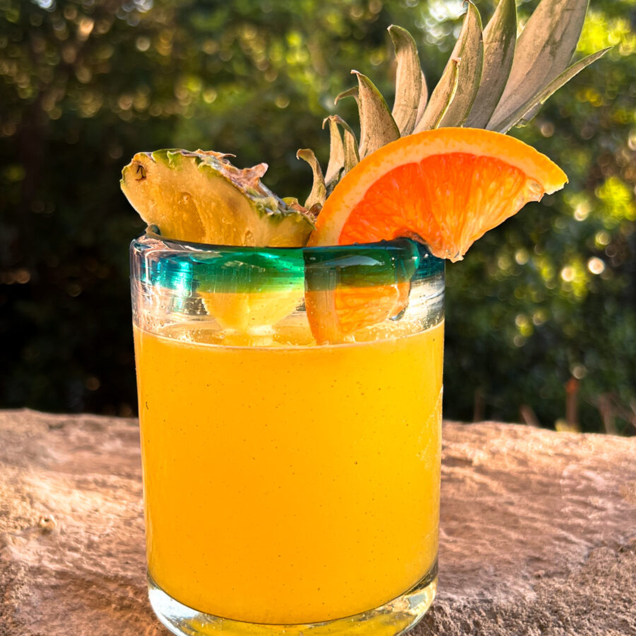 fresh pineapple margarita on the rocks with a pineapple spear and orange