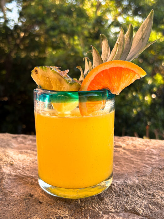 fresh pineapple margarita on the rocks with a pineapple spear and orange