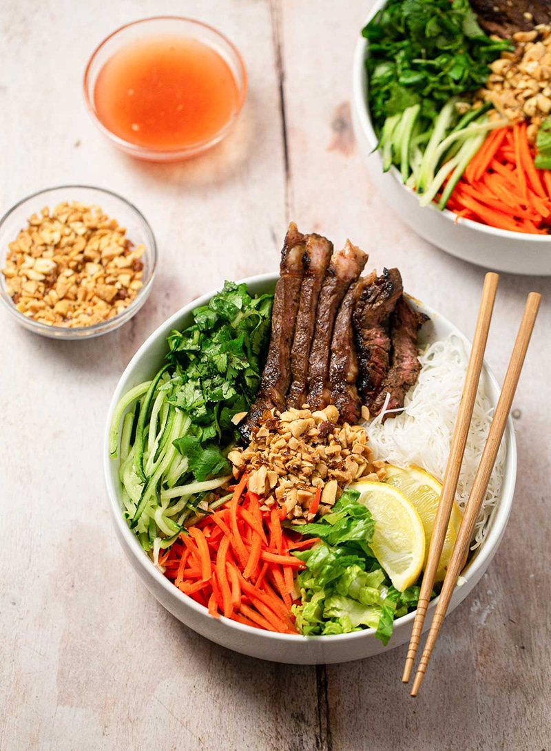 Asian beef noodle bowl woth chopsticks and peanuts and veggies