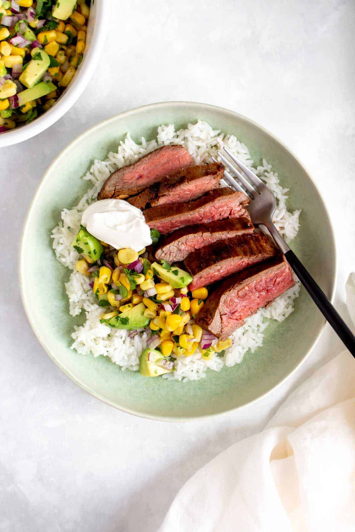 Steak bowl with cut rare steak and rice and corn and sour cream