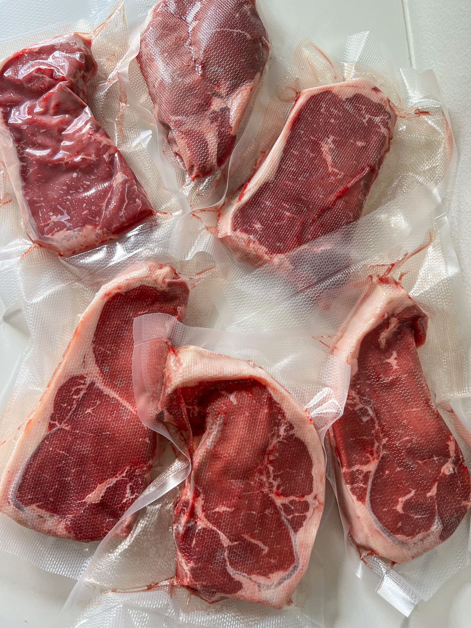 Strip steaks that have been vacuum sealed in plastic