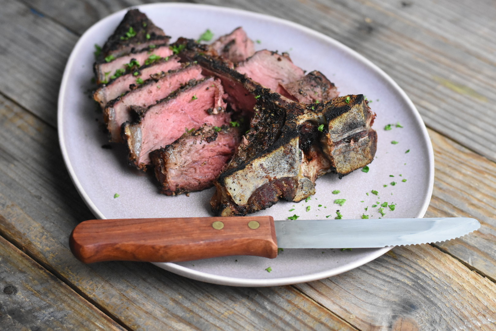 Medium rare t bone steak sliced on a plate with a steak knife