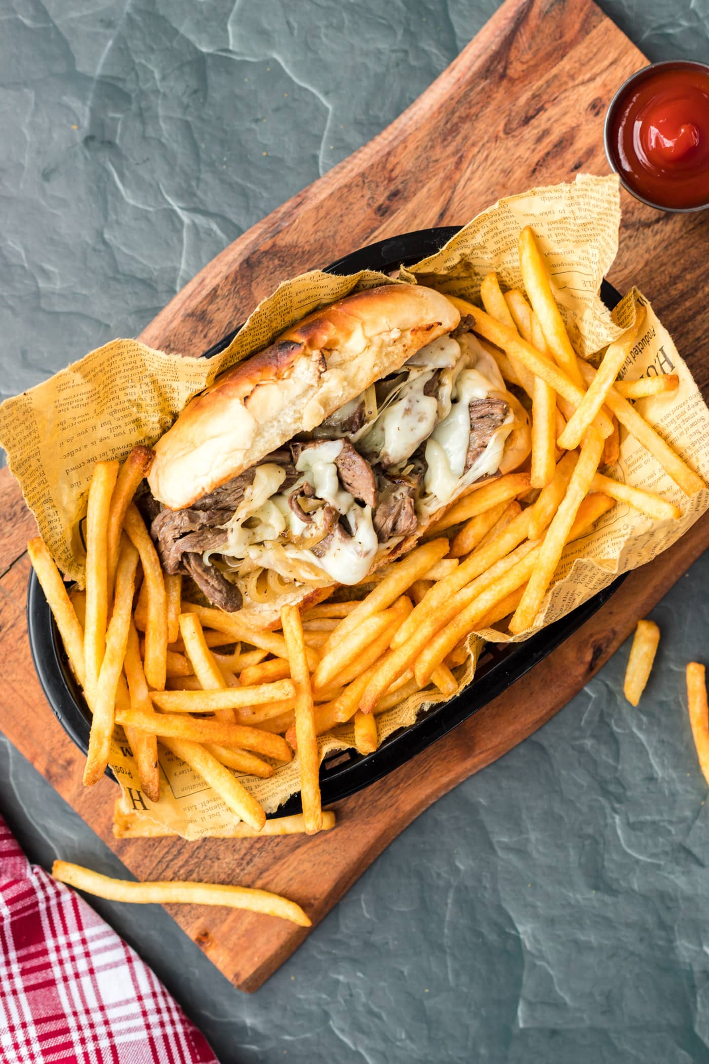 philly cheese steak sandwich in a basket with french fries