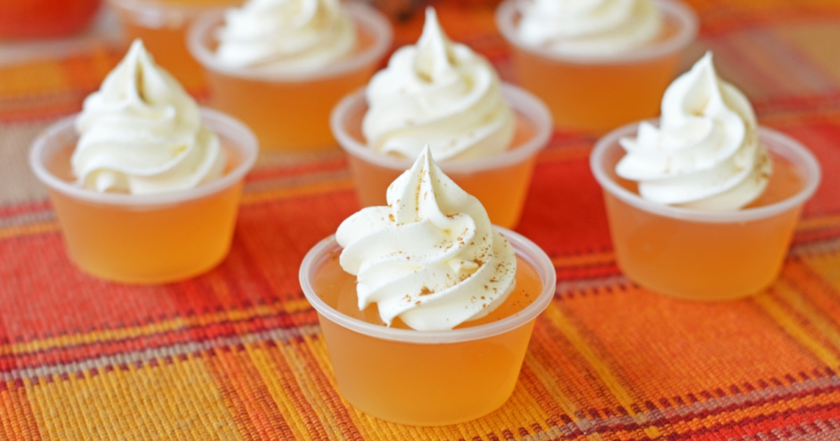 apple cider jello shots with whipped cream on a plaid backround
