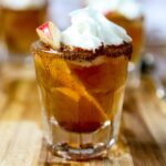 apple pie fireball shot with an apple slice and whipped cream