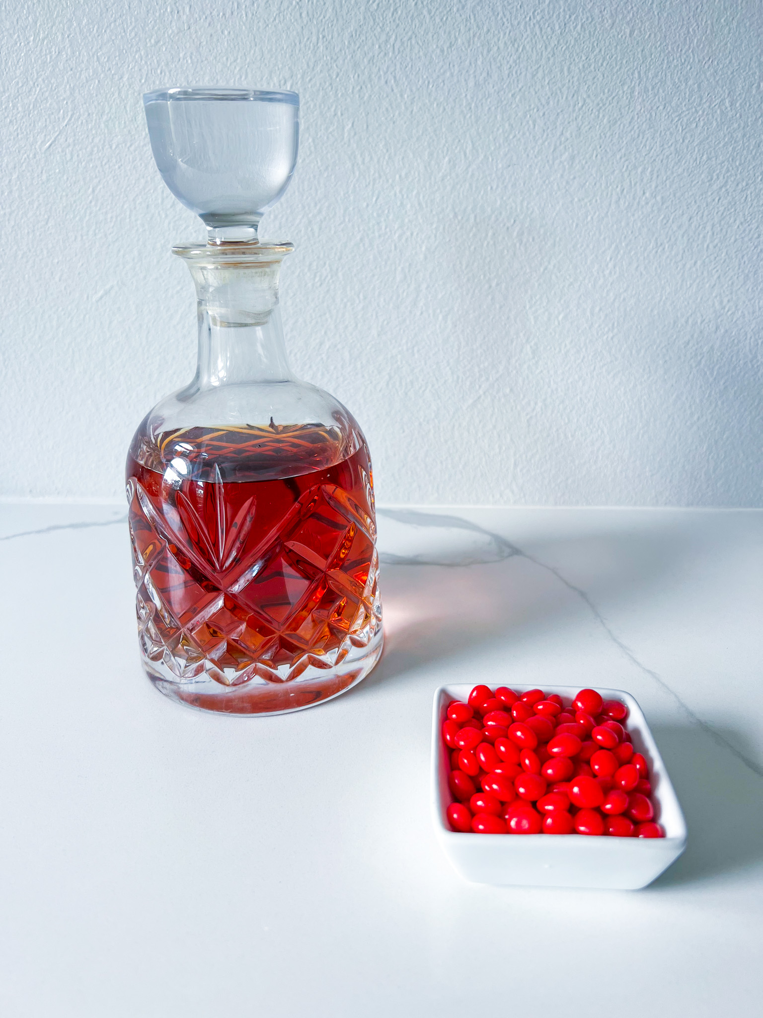 Bourbon in a decanter with a lid and a bowl of red hot candies