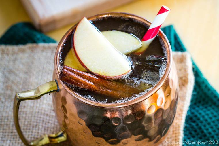 spiced apple cider moscow mule made with fireball in a copper mug with apples and a straw