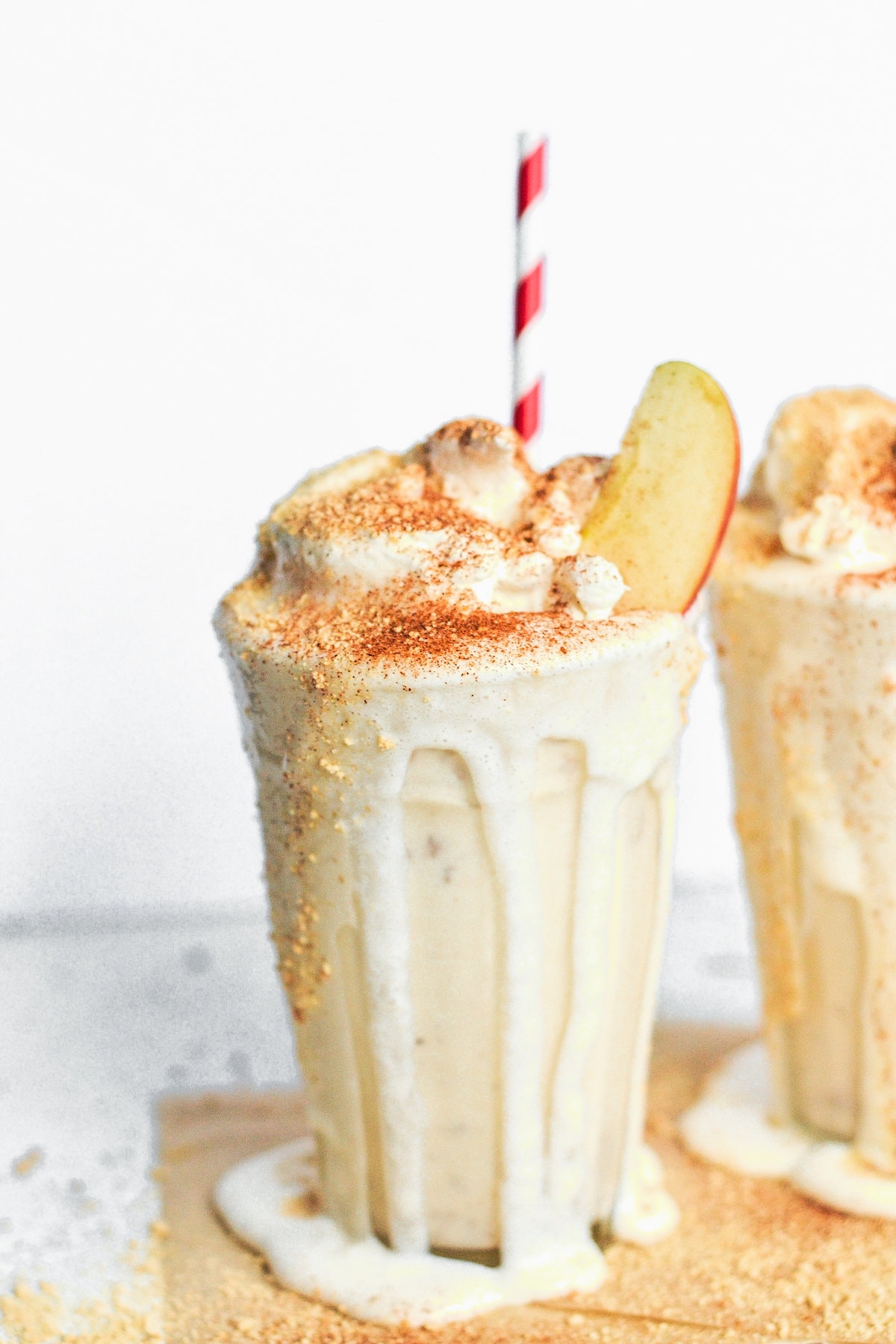 2 apple pie milkshakes with apples in them and a red and white straw