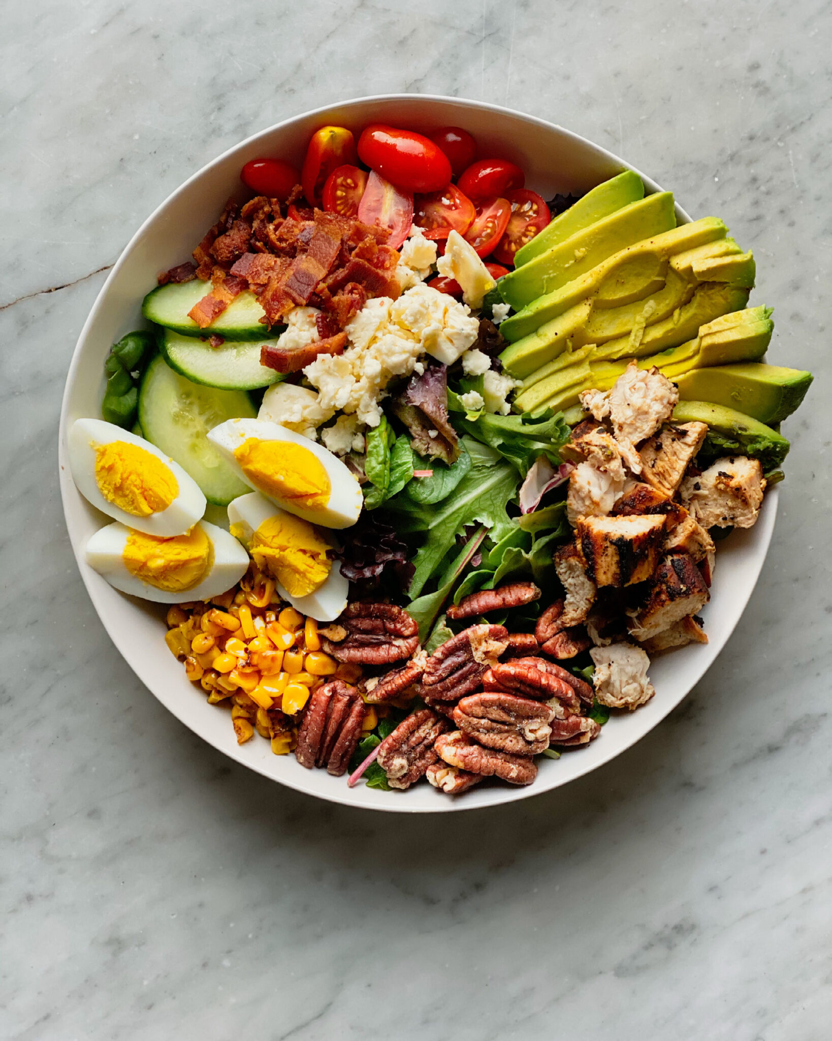 Chicken salad with avocado, roasted pecans, cor, eggs, cucumbers and bacon