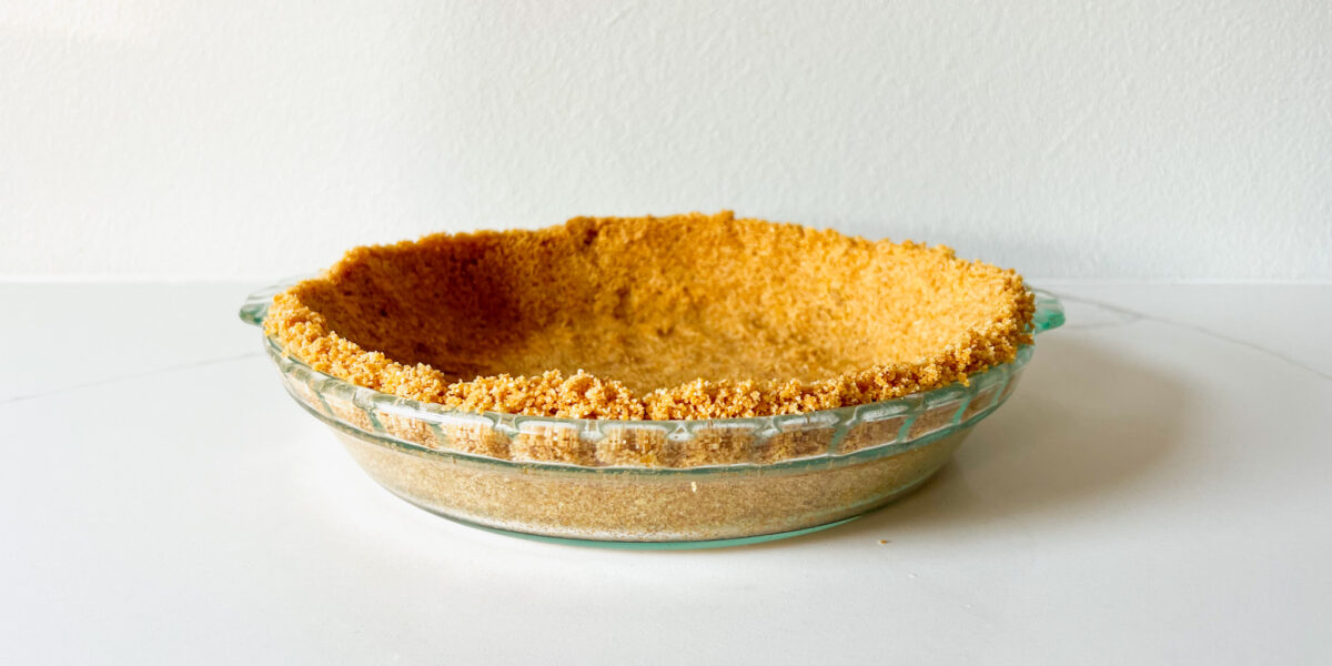 Graham cracker crust in a pie dish on a white table