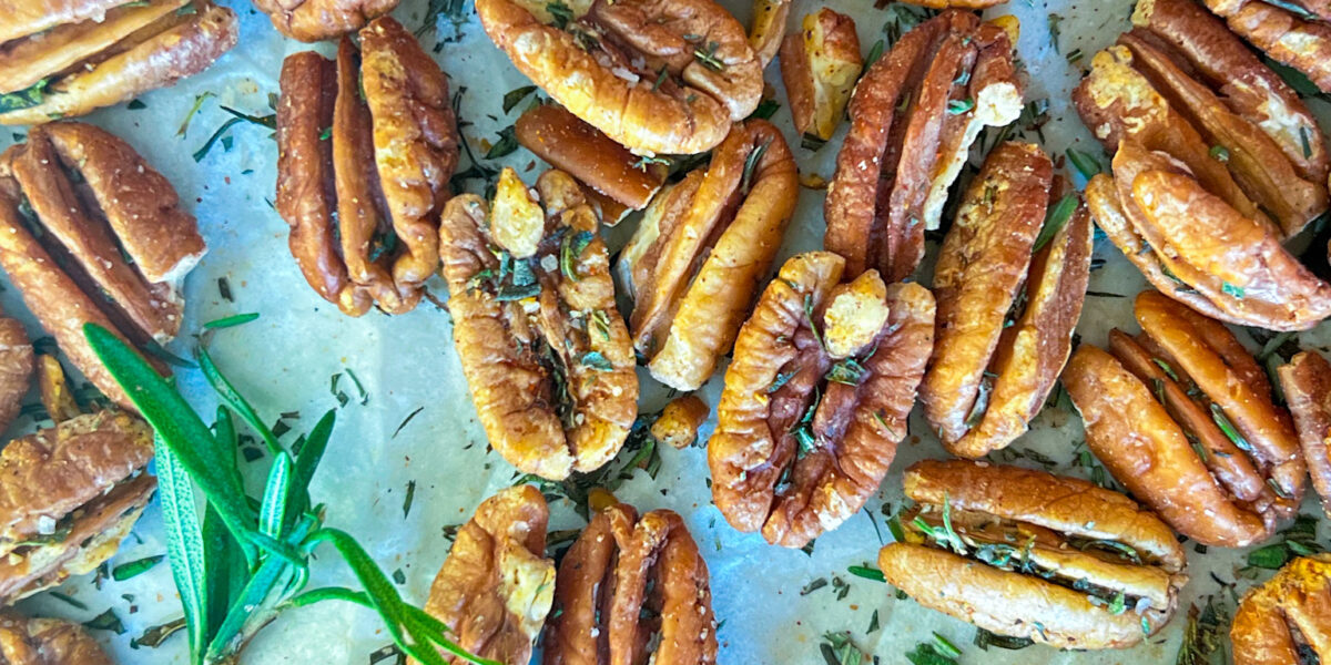 roasted pecans with rosemary on a sheet pan