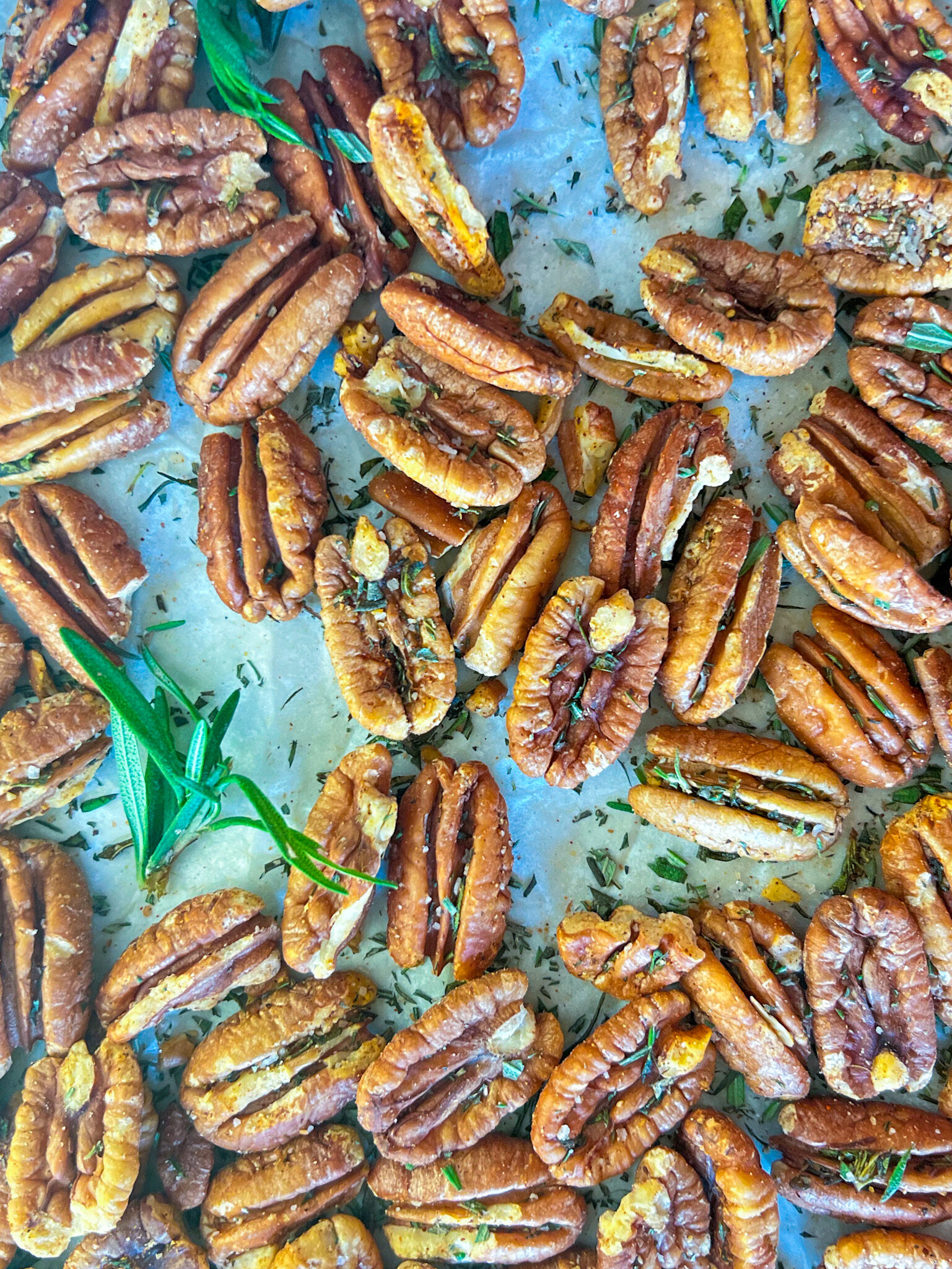 roasted pecans with rosemary on a sheet pan