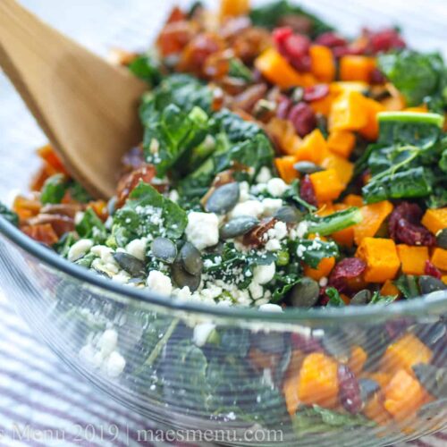 kale salad with dates and squash in a bowl with a spoon