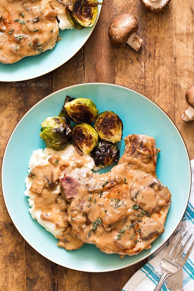 pork chops with mushroom gravy on a blue plate with brussell sprouts