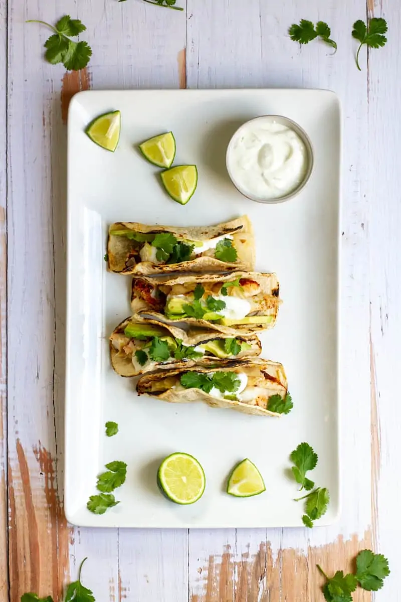 fish tacos on a platter with lime and sour cream