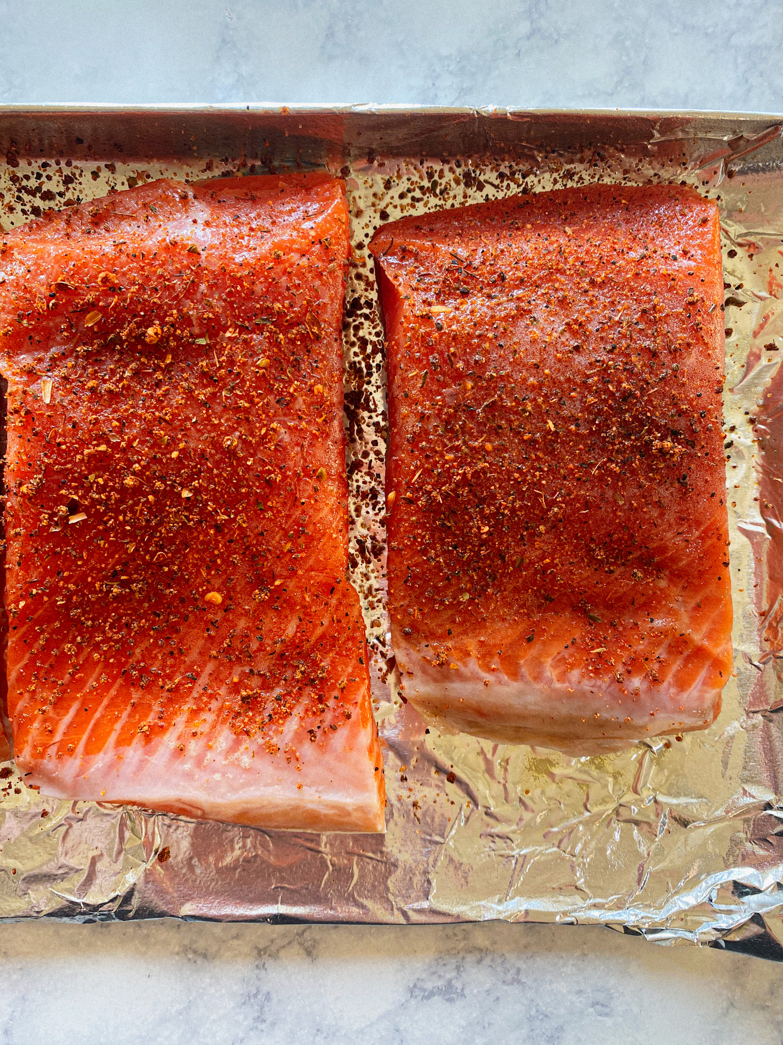 2 pieces of salmon with blackened seasoning on them on foil