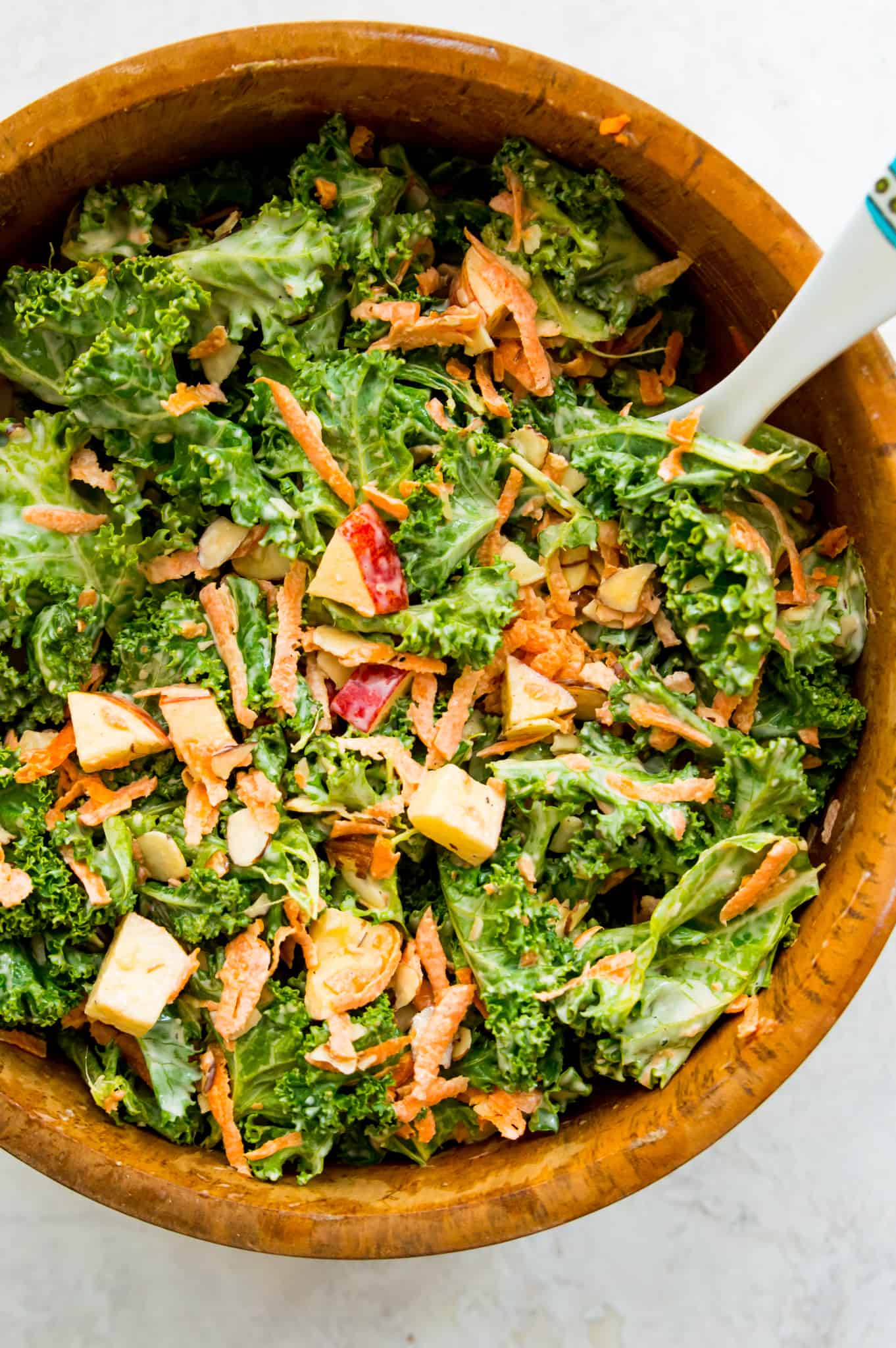 Kale and apple slaw in a wooden bowl with a spoon