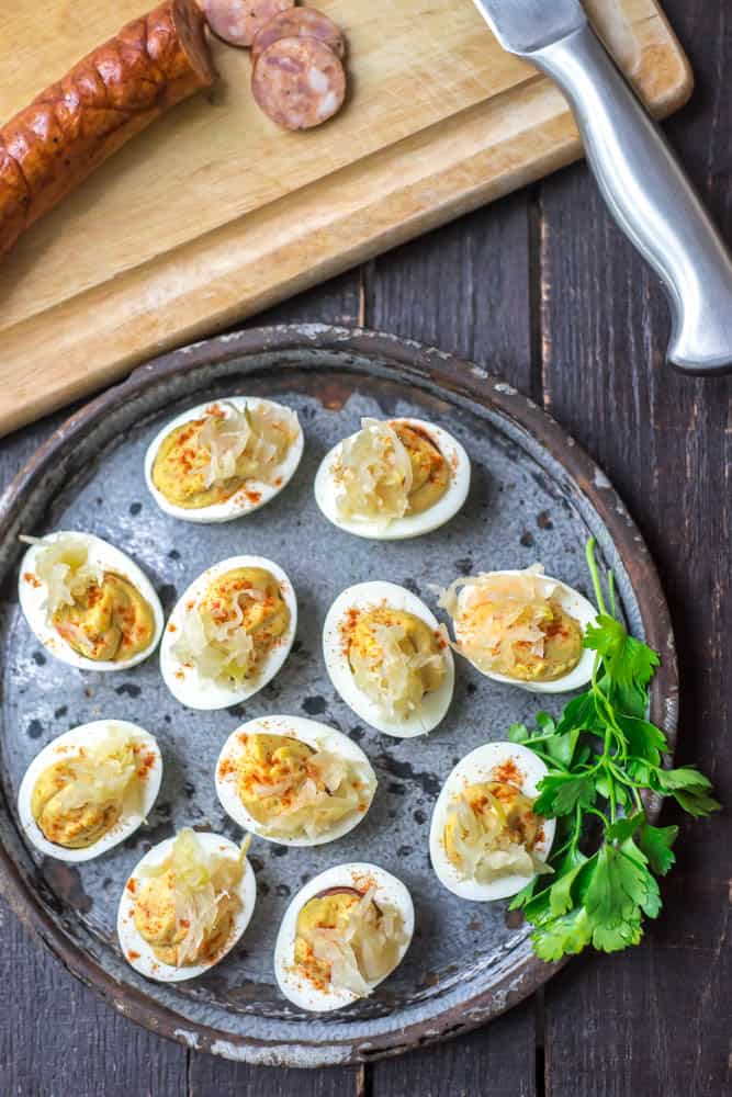 cajun deviled eggs made with sausage on a round plate with some herbs