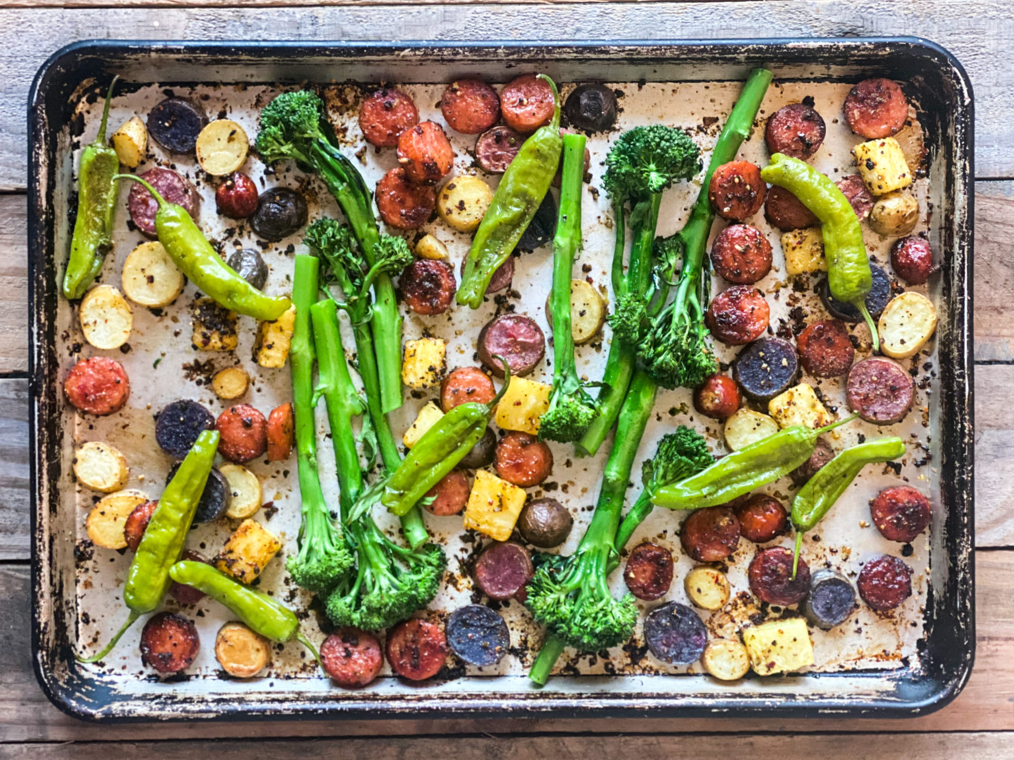 Sheet pan of sausages with broccolini, pinapple and shishito peppers