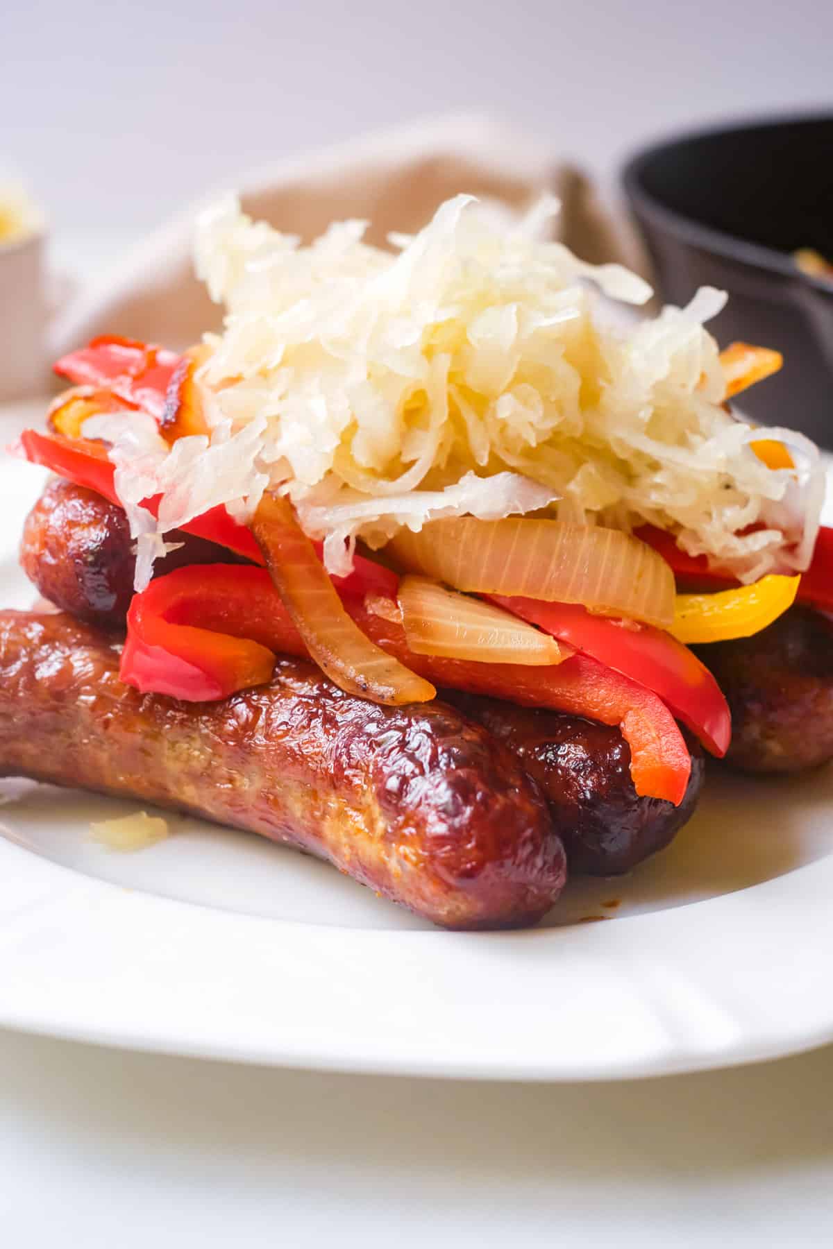 Air-fryed bratwurst on a plate with peppers and sourkraut