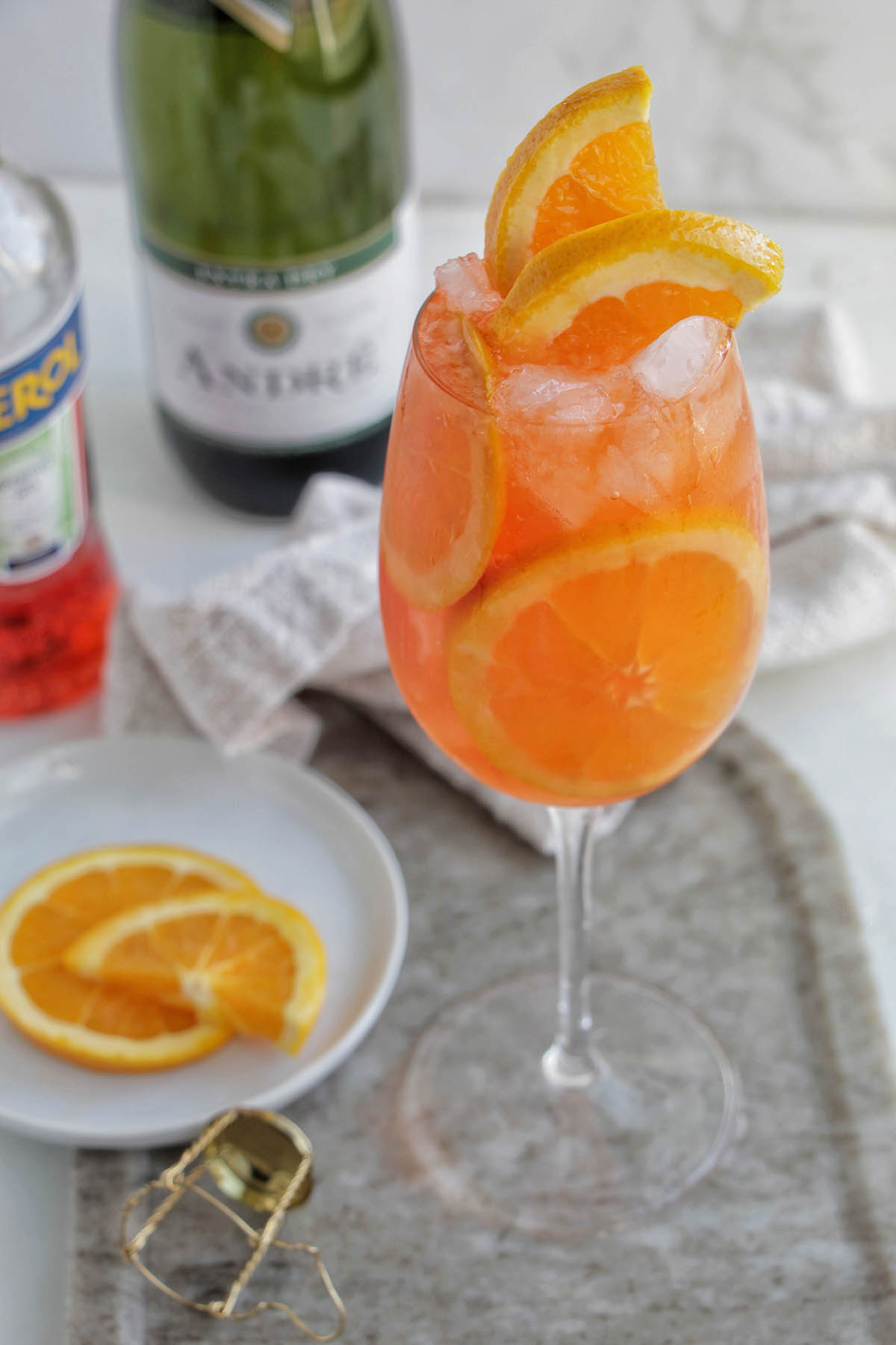 Italian aperol spritz in a wine glass with oranges and slices of oranges on a plate