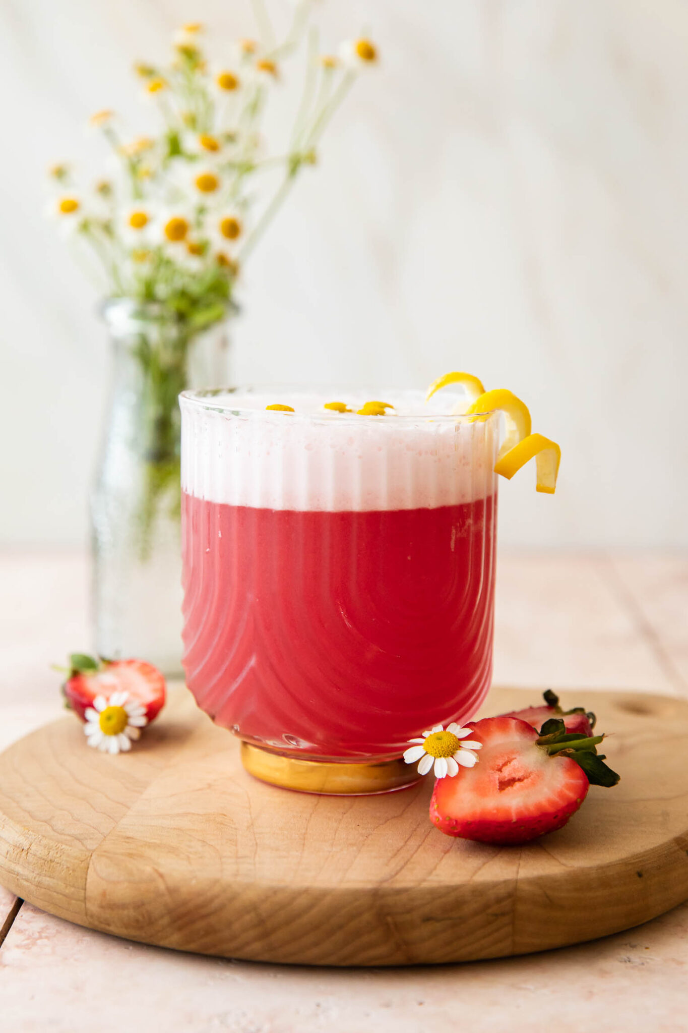 Pink gin sour with lemon garnish and strawberries