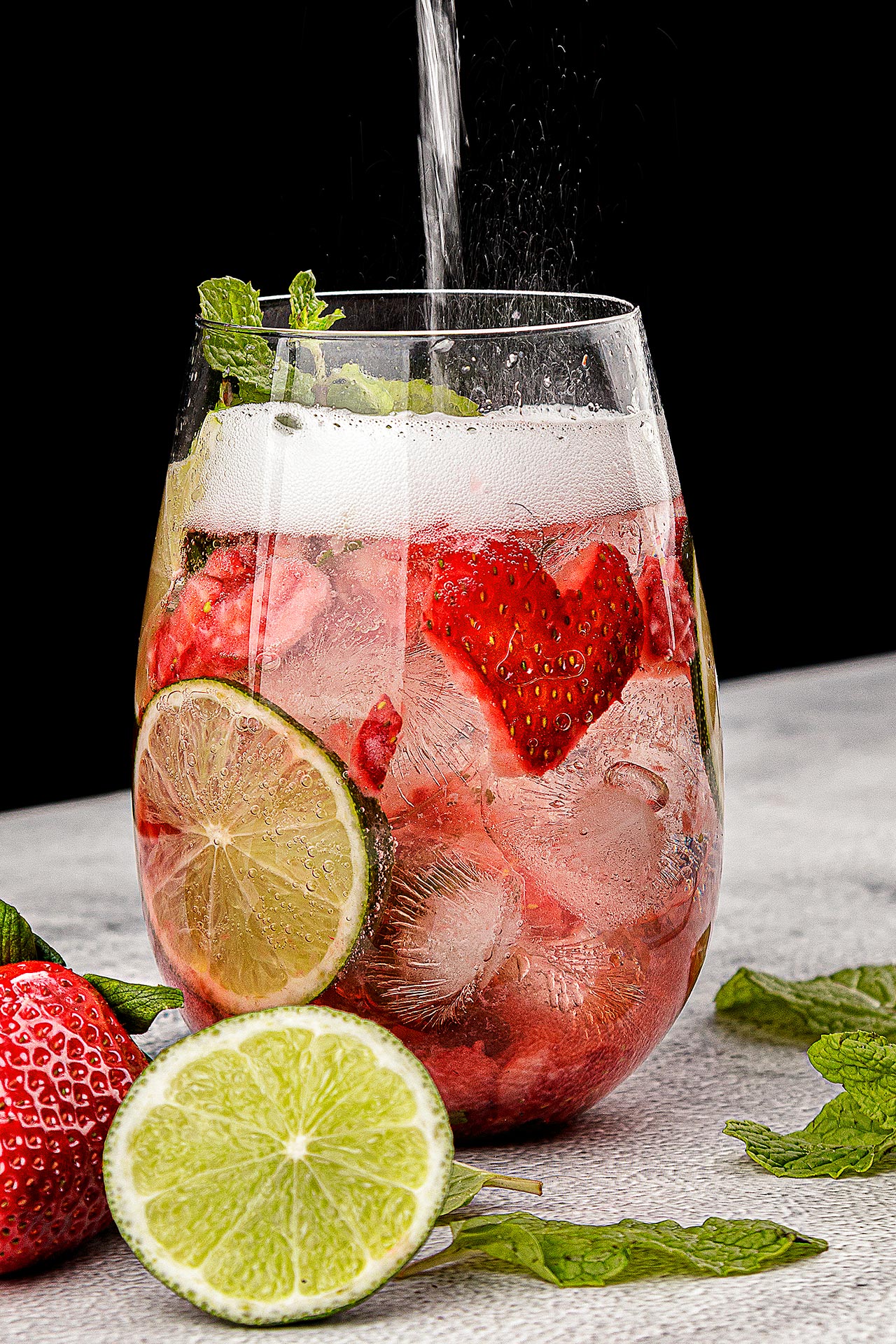 strawberry mocktail with heart shaped strawberries and soda water being poured into glass