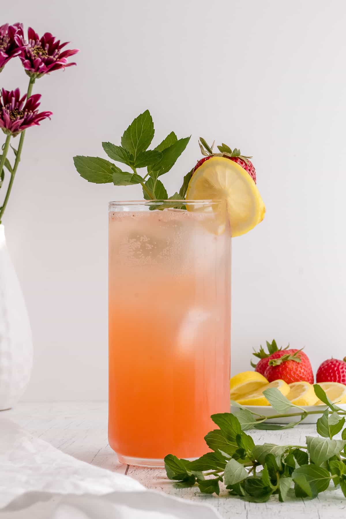 Strawberry vodka lemonade in a tall glass with a lemon wedge and ice